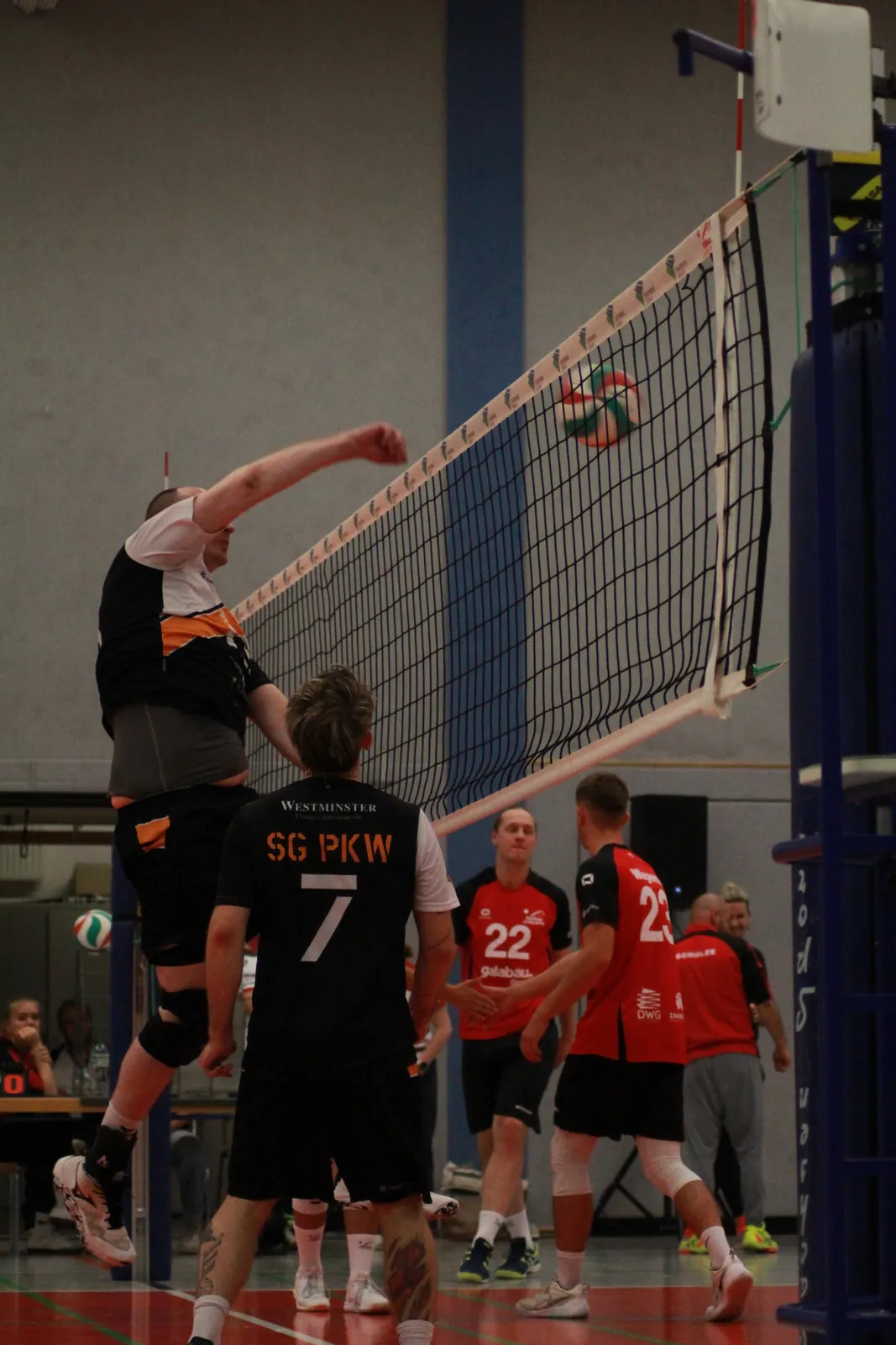 Angreifer schlaegt den Ball gegen zwei Blockspieler