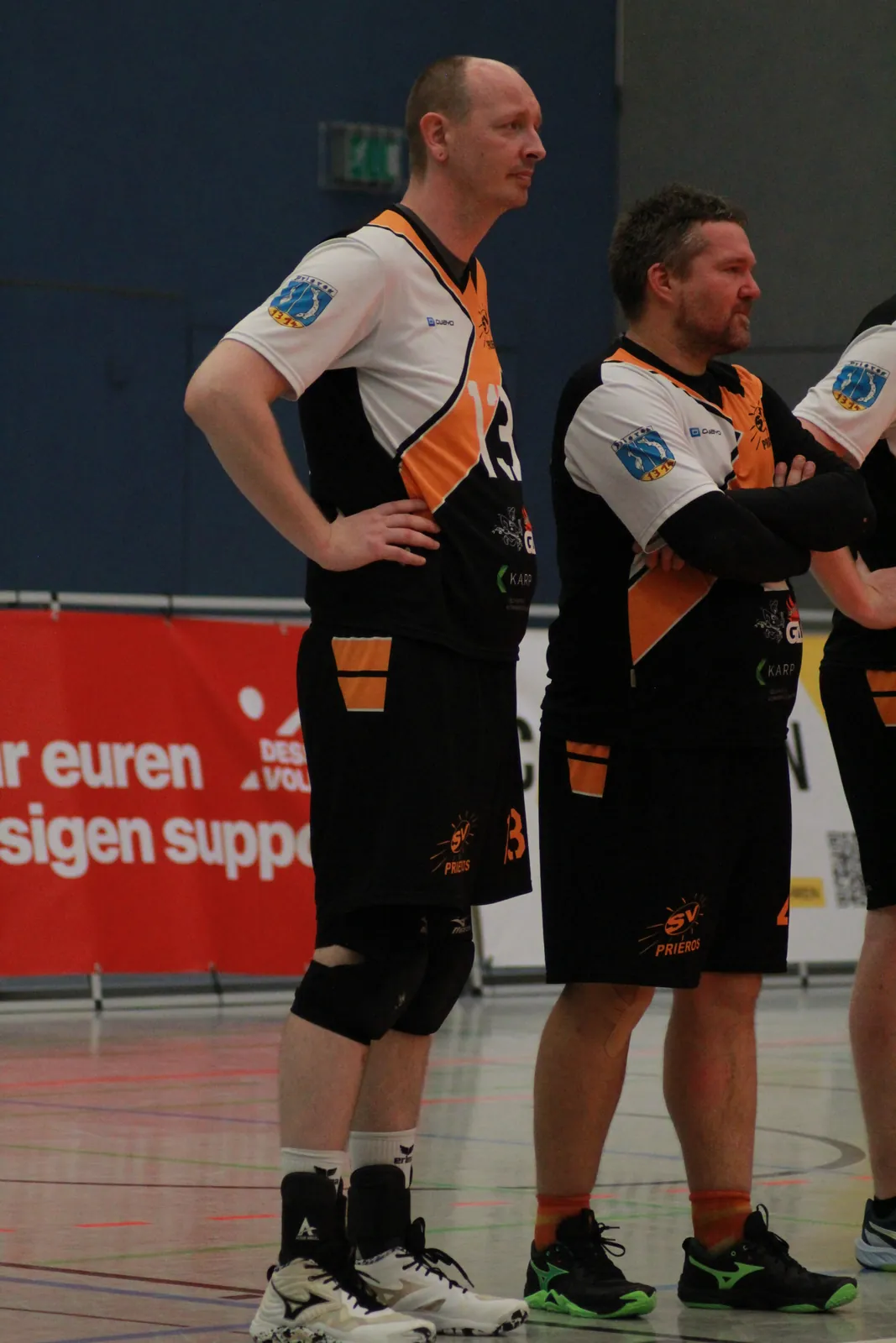 Zwei Spieler stehen am Spielfeldrand und verfolgen das Spiel