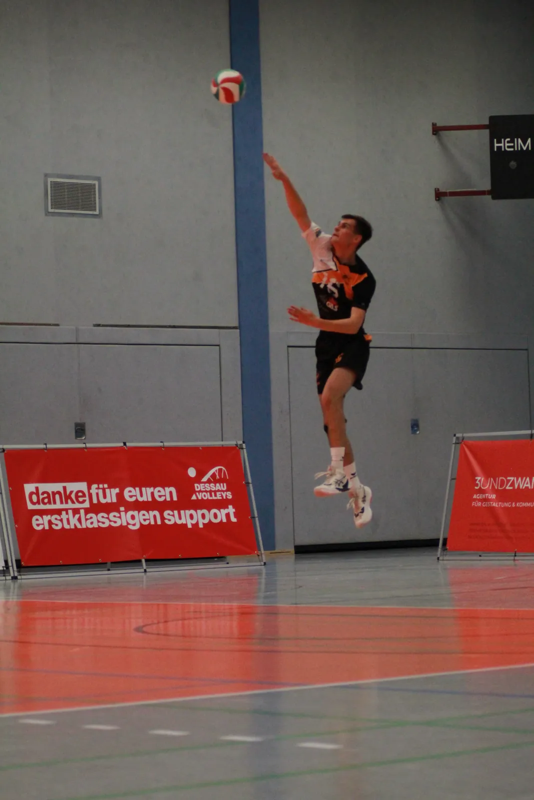Volleyballspieler im Sprungaufschlag, der Ball schwebt über ihm